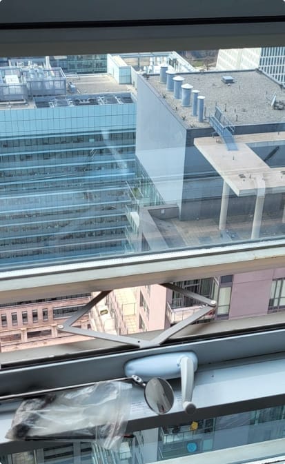 A view from a high vantage point showcasing urban architecture, with a focus on a security camera attached to the window sill, overlooking the cityscape through Icarus Services-installed windows.