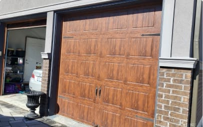 A residential garage with an open door revealing storage items inside, featuring client-approved closed wooden paneled garage doors under clear skies.